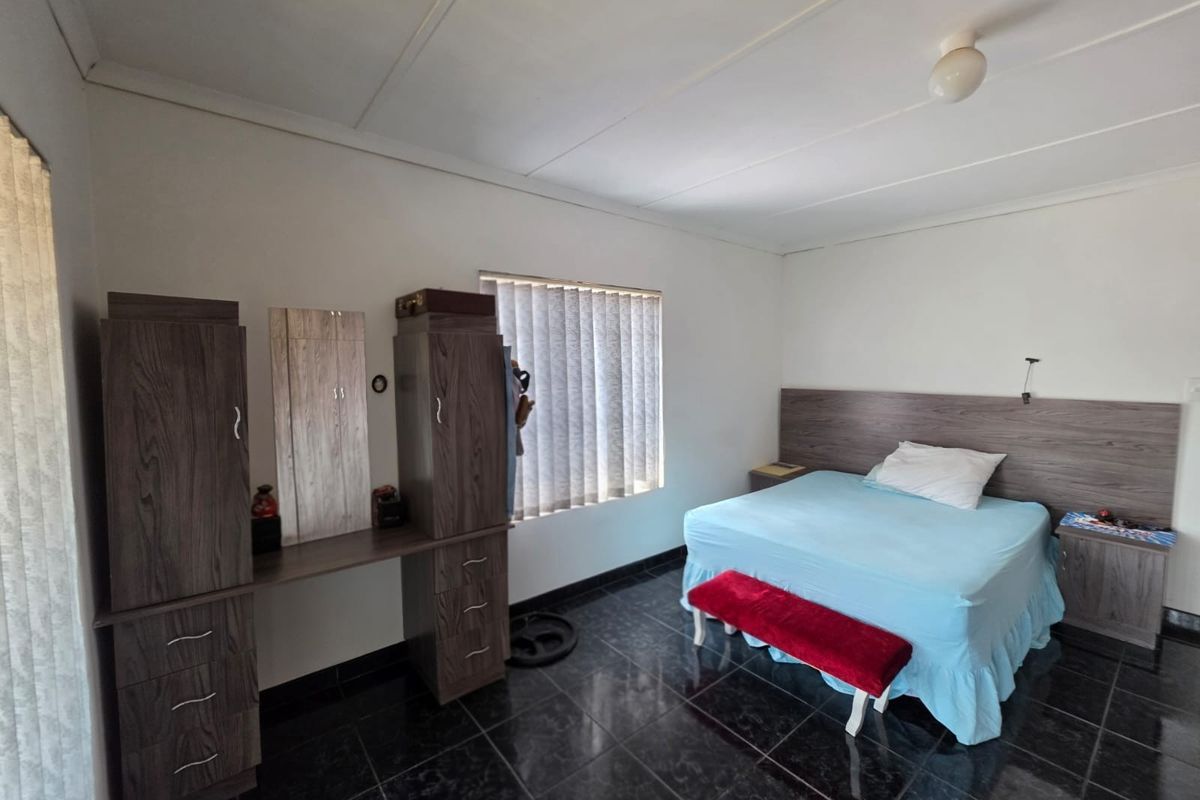 A bedroom featuring dark tiled flooring, built-in cupboards with a vanity section, and a built-in headboard with matching bedside pedestals.