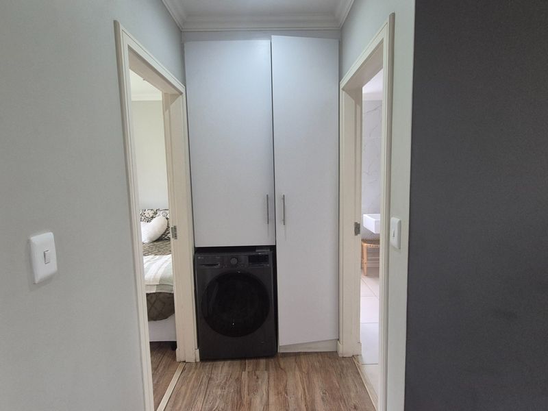 A compact laundry area featuring built-in cabinetry for storage, conveniently located within the hallway.