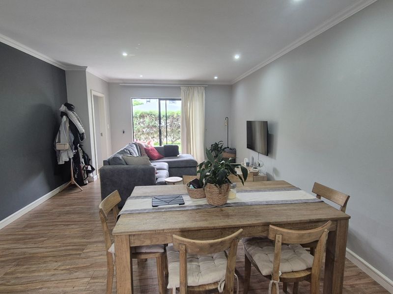 Spacious open-plan living and dining area featuring modern laminate flooring, recessed downlighting, and a large sliding glass door providing natural light.