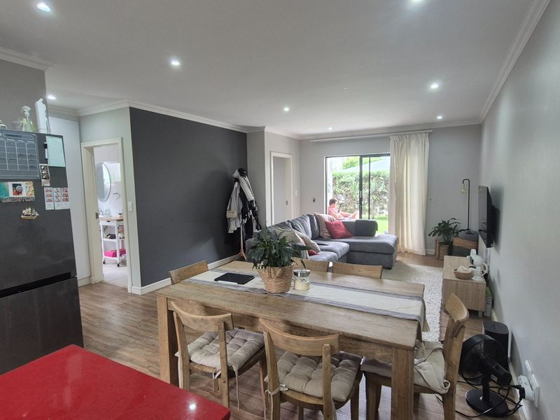 Open-plan living and dining area featuring laminate flooring, recessed downlighting, and a sliding glass door providing access to the outdoor space.