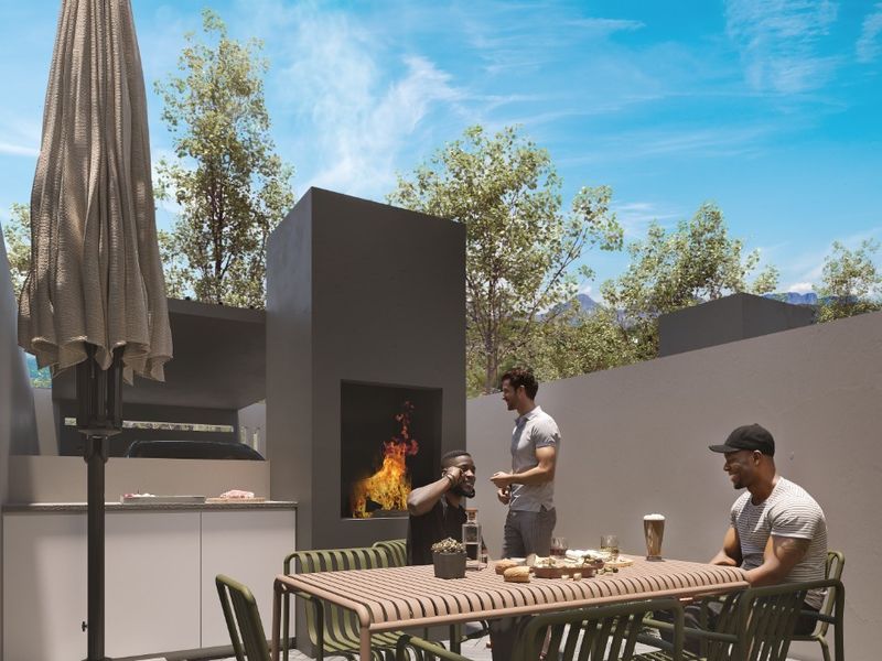 Modern outdoor patio area featuring a built-in fireplace, integrated kitchen counter, and stylish herringbone paving, perfect for alfresco dining and entertaining.