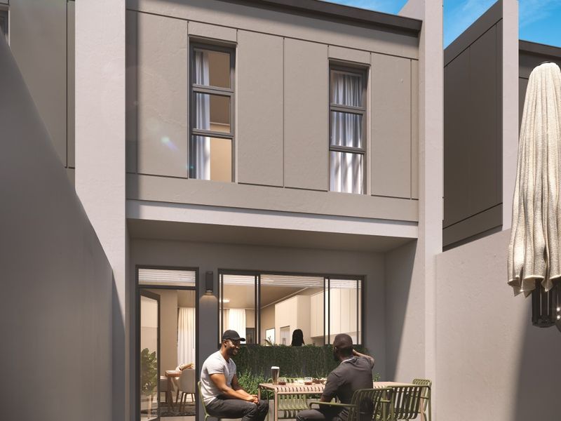 A modern rear patio area featuring herringbone paving, sleek architectural facade, and seamless access to the interior living space through large sliding glass doors.