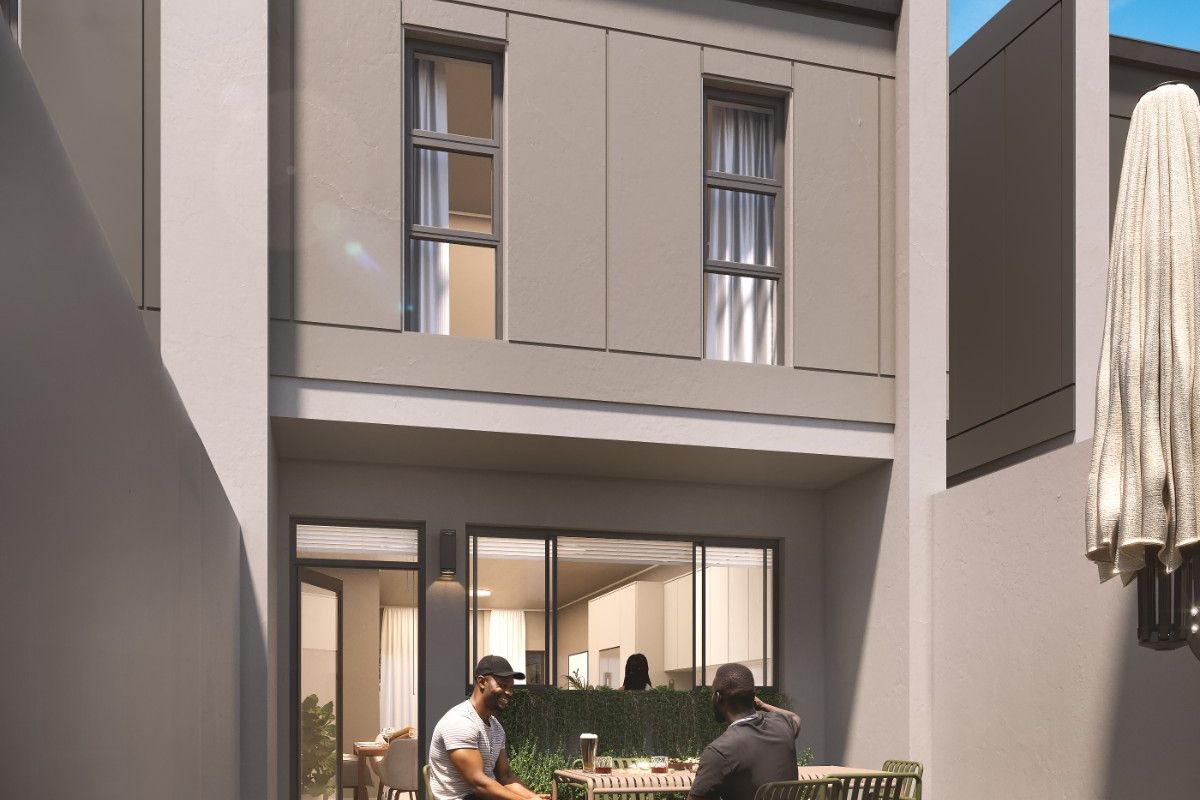 A modern rear patio area featuring herringbone paving, sleek architectural facade, and seamless access to the interior living space through large sliding glass doors.
