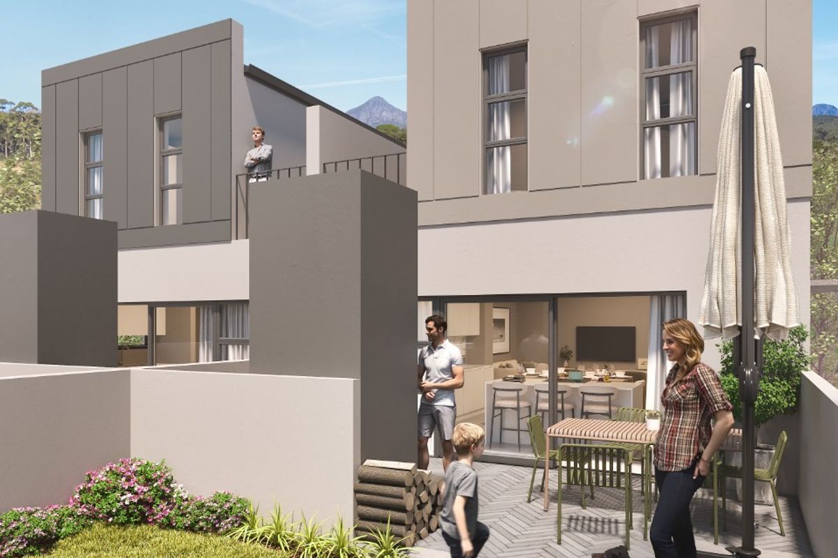Modern rear exterior view featuring a paved patio area, landscaped garden, and upper-level balcony with contemporary architectural finishes.
