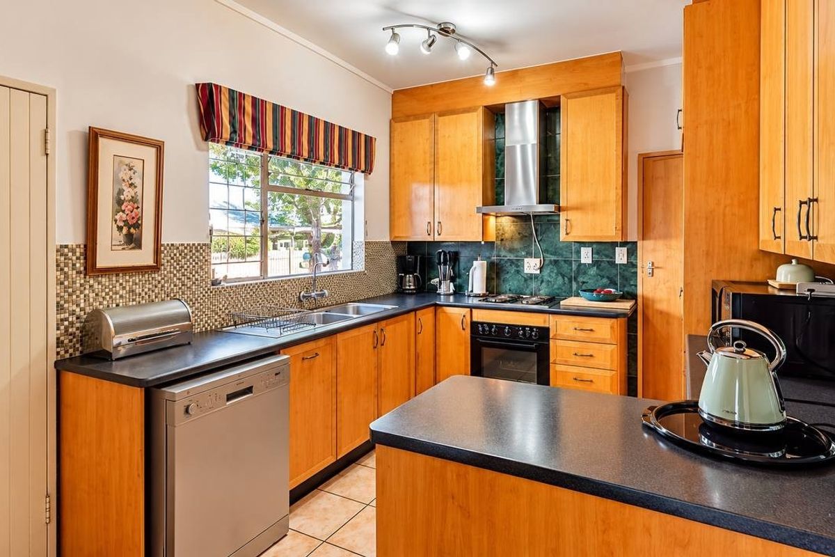A functional kitchen featuring wooden cabinetry, laminate countertops, a built-in oven with gas hob, and a tiled backsplash.