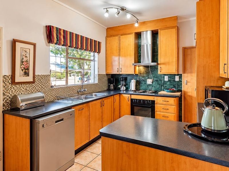 A functional kitchen featuring wooden cabinetry, laminate countertops, a built-in oven with gas hob, and a tiled backsplash.