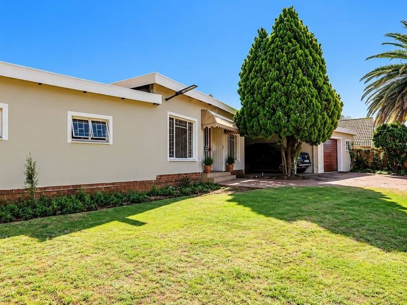 A well-maintained front exterior view of the house featuring a neat lawn, brick driveway, and integrated garage.