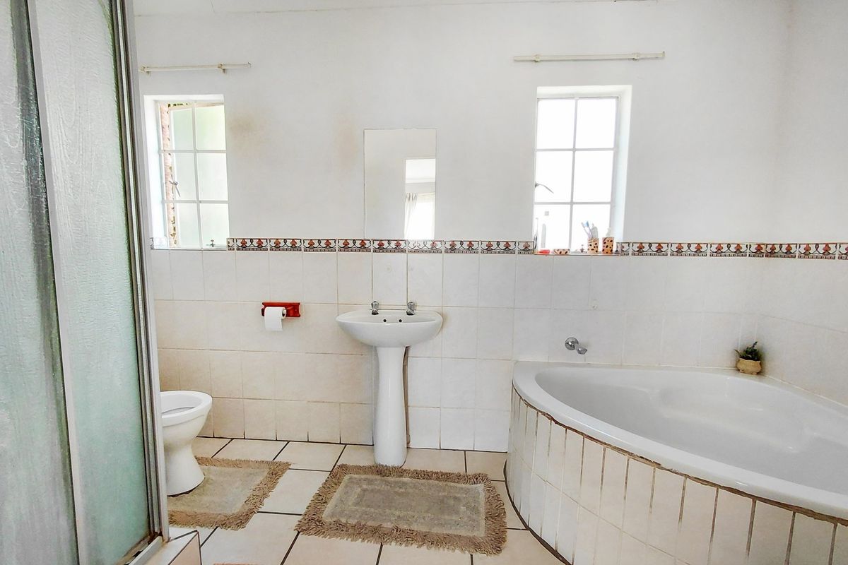 A functional bathroom featuring a corner bathtub, separate shower enclosure, pedestal basin, and toilet with classic tiled finishes.