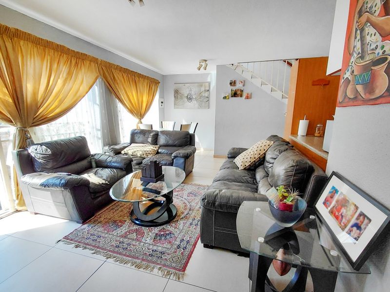 Open plan living area featuring tiled flooring, a breakfast counter, and a staircase leading to the upper level.