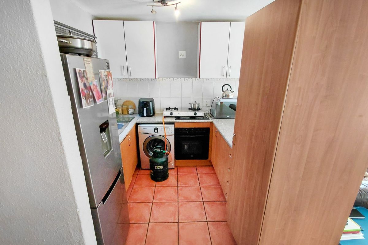 Compact kitchen featuring built-in cabinetry, gas hob, oven, and tiled flooring, offering a functional layout for daily meal preparation.