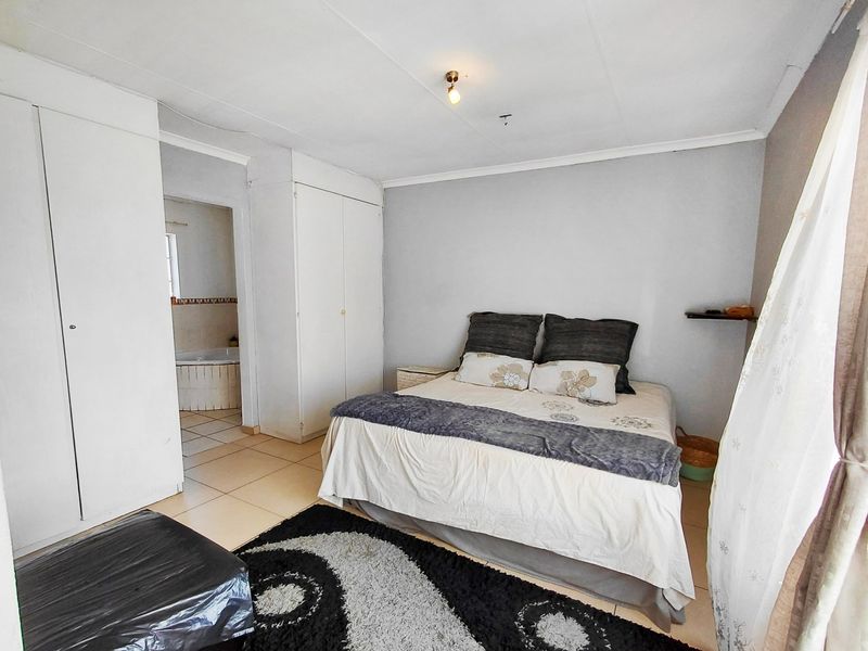 A bedroom featuring built-in cupboards, tiled flooring, and direct access to an en-suite bathroom.