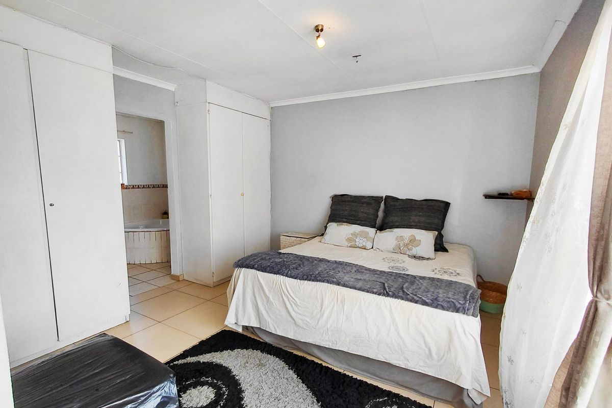 A bedroom featuring built-in cupboards, tiled flooring, and direct access to an en-suite bathroom.