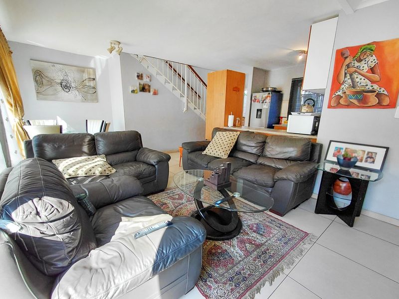 Open plan living area featuring tiled flooring and a staircase, seamlessly connecting to the kitchen space.