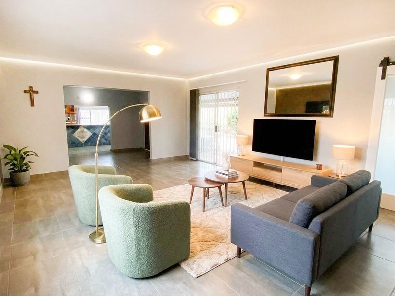 Spacious living room featuring tiled flooring, recessed ceiling lighting, and a sliding glass door providing access to the exterior.