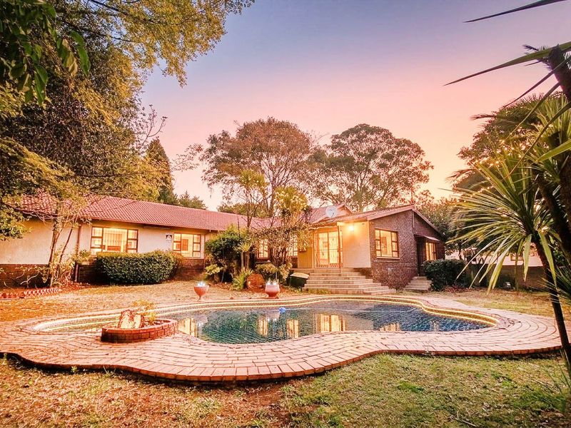 Rear view of the house featuring a swimming pool with brick paving, established garden, and direct access to the home via concrete steps.