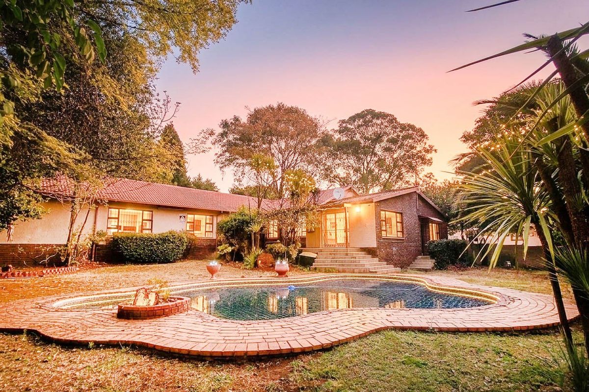 Rear view of the house featuring a swimming pool with brick paving, established garden, and direct access to the home via concrete steps.