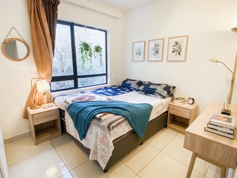 A well-lit bedroom featuring neutral tiled flooring and a large window that provides natural light.
