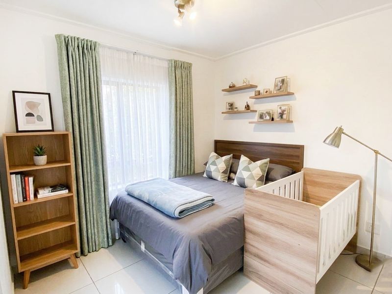 A well-maintained bedroom featuring tiled flooring, neutral walls, and a large window with installed curtain tracks.