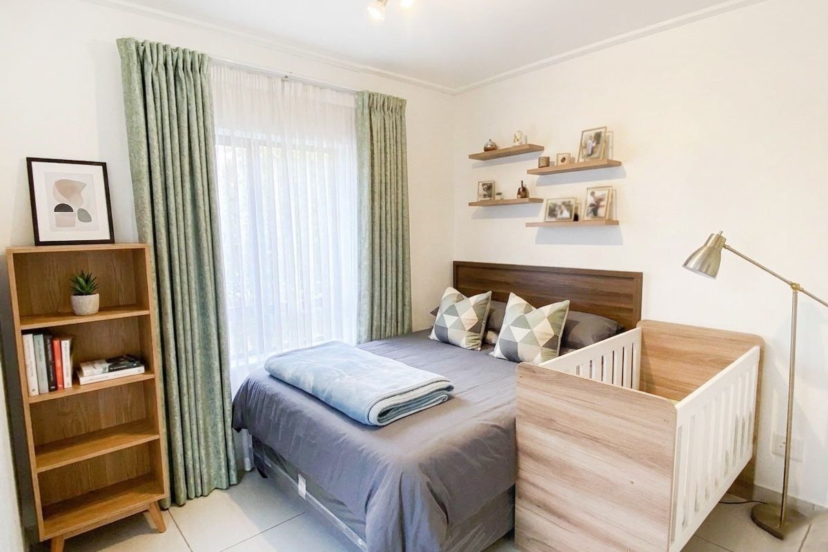 A well-maintained bedroom featuring tiled flooring, neutral walls, and a large window with installed curtain tracks.