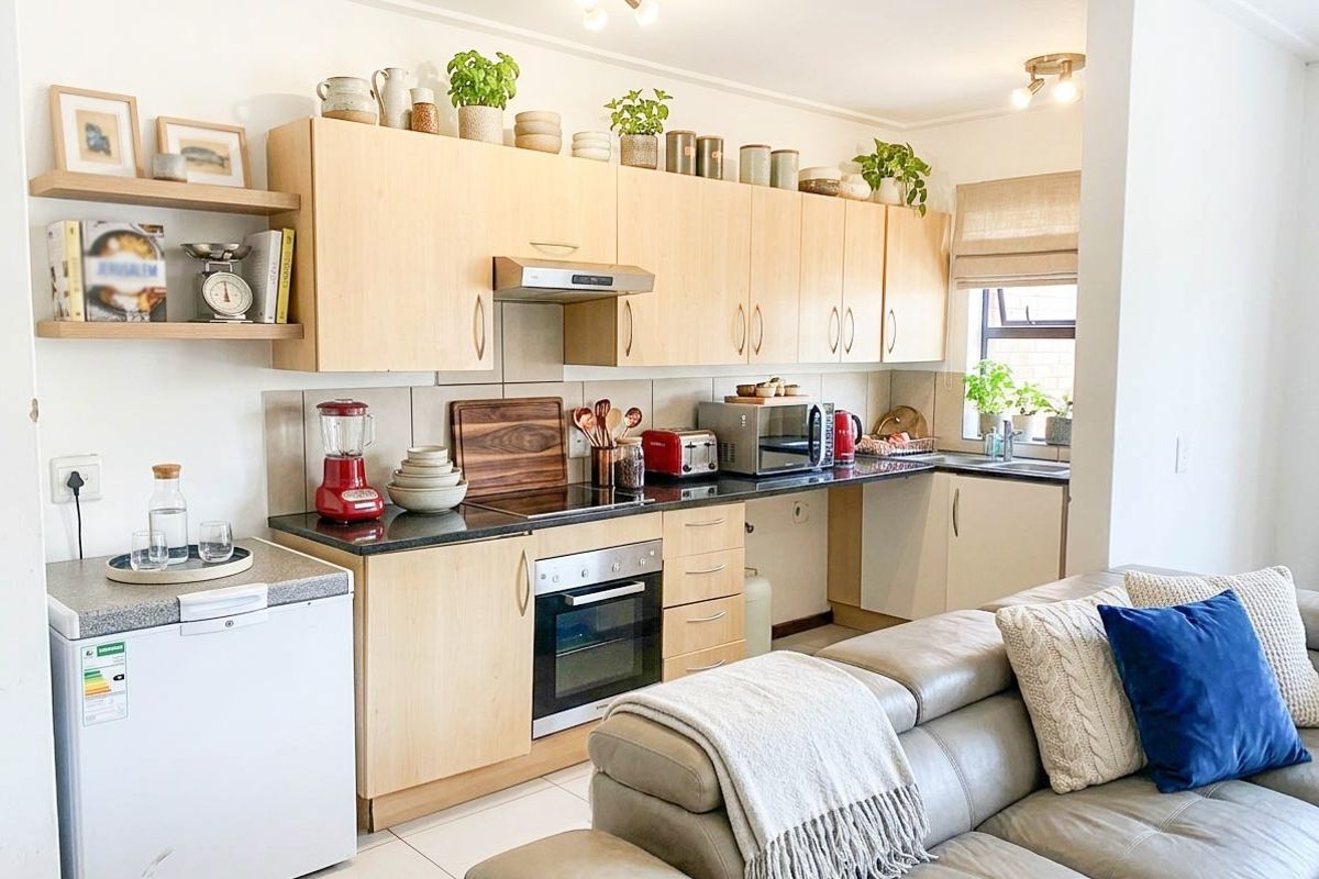 An open-plan kitchen featuring light-wood cabinetry, black granite countertops, built-in oven, and hob, seamlessly integrated with the living area.