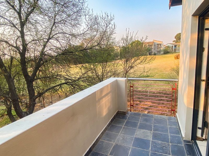 A private balcony featuring tiled flooring and a metal balustrade, offering pleasant views of the surrounding landscape and estate grounds.