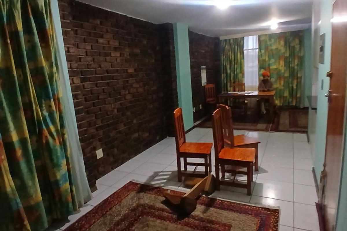 A living area featuring an exposed brick feature wall and tiled flooring, offering a functional space with potential for modern updates.
