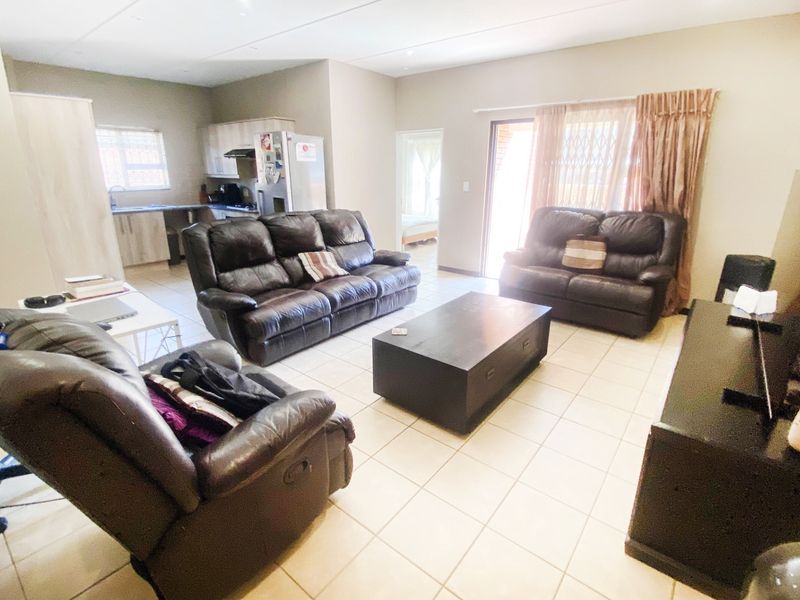 Open-plan living area featuring tiled flooring, integrated kitchen cabinetry, and a sliding door providing access to the exterior.