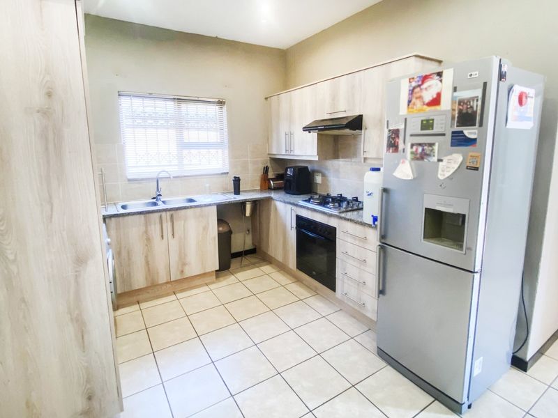 A functional kitchen featuring light wood-tone cabinetry, granite countertops, a built-in oven with gas hob, and tiled flooring.
