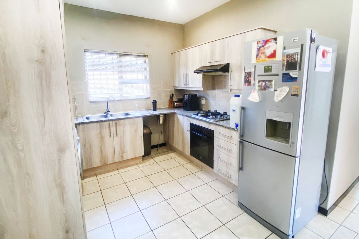 A functional kitchen featuring light wood-tone cabinetry, granite countertops, a built-in oven with gas hob, and tiled flooring.