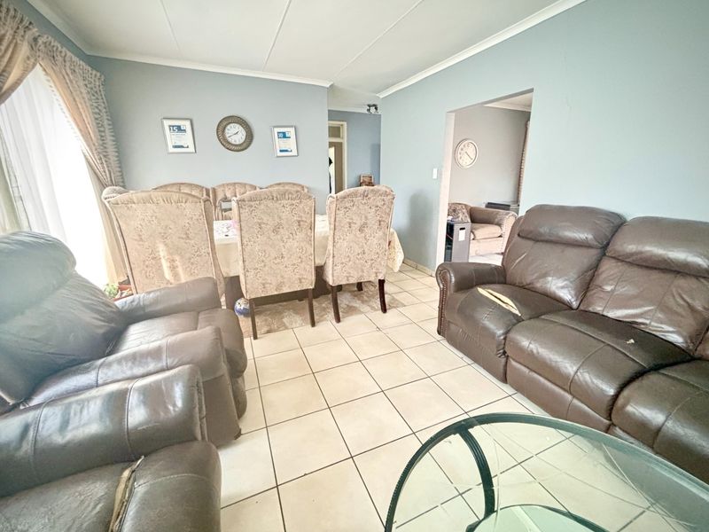 Open plan living and dining area featuring neutral tiled flooring and coved ceilings, providing a functional space for family gatherings.