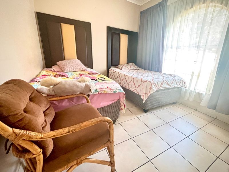 A bedroom featuring tiled flooring and an arched window with curtain rails, providing a functional space with natural light.