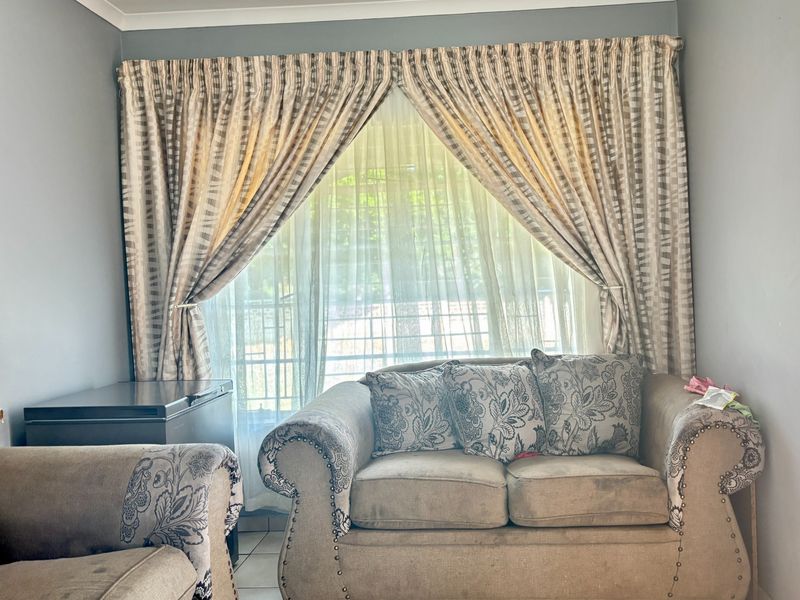 A living room area featuring tiled flooring and large window treatments, providing a neutral base for interior design updates.