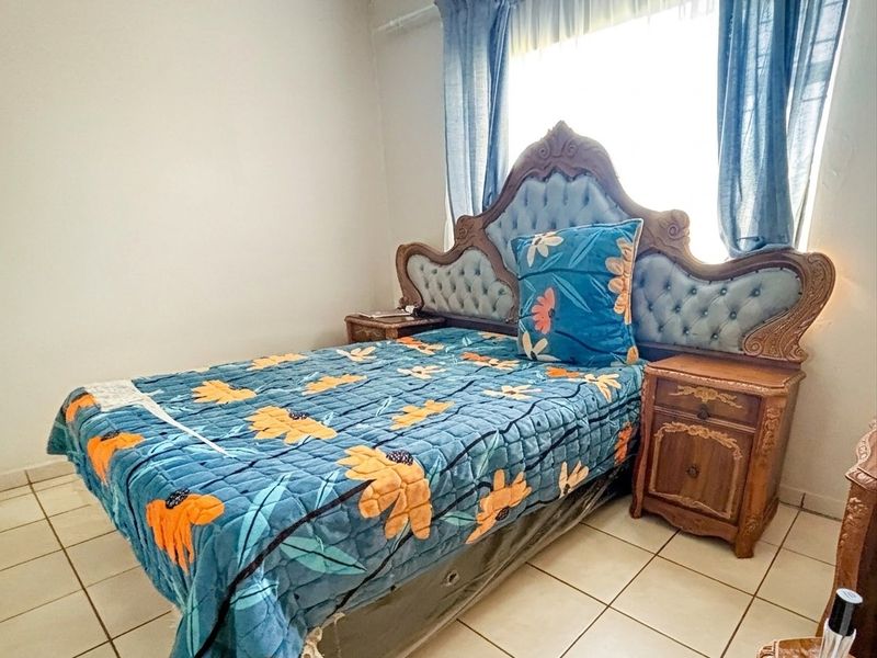 A bedroom featuring tiled flooring and a window with curtain rod installation.