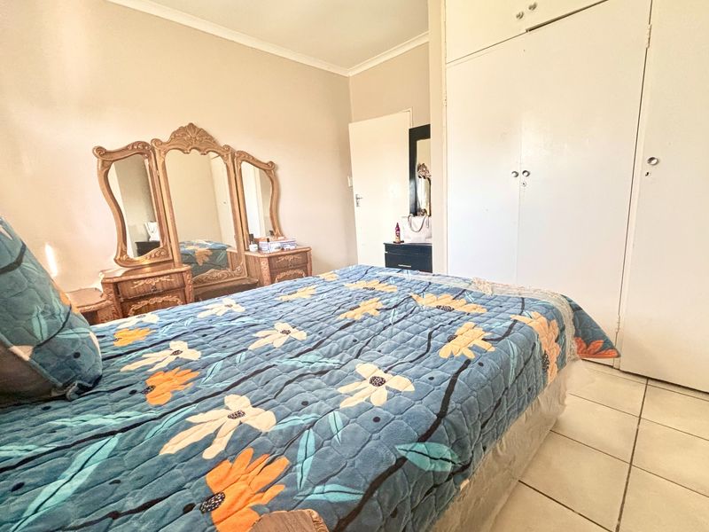 A bedroom featuring tiled flooring, coved cornicing, and built-in cupboards, offering a functional space with potential for modern updates.