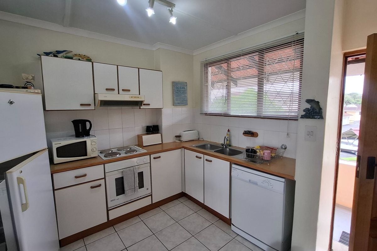 Functional kitchen featuring white cabinetry, laminate countertops, built-in oven, electric hob, and tiled flooring with direct access to an outdoor area.
