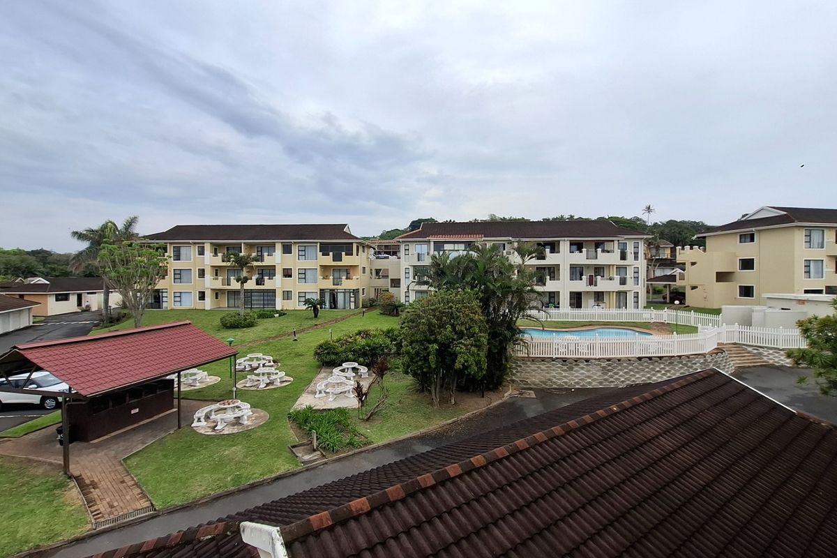 Elevated view of the apartment complex grounds featuring a swimming pool, communal garden, and covered outdoor seating area.