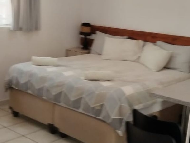 A functional bedroom featuring tiled flooring, a ceiling light fixture, and an integrated air conditioning unit.