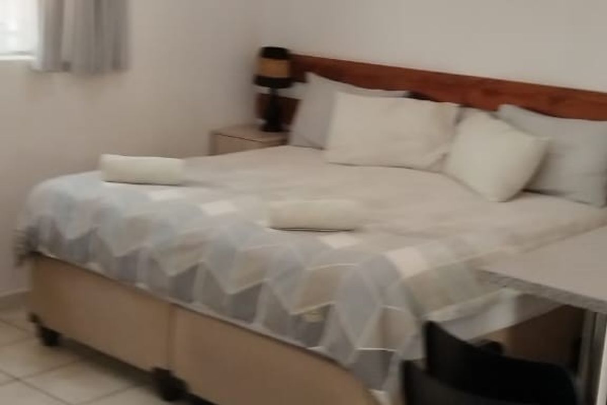 A functional bedroom featuring tiled flooring, a ceiling light fixture, and an integrated air conditioning unit.