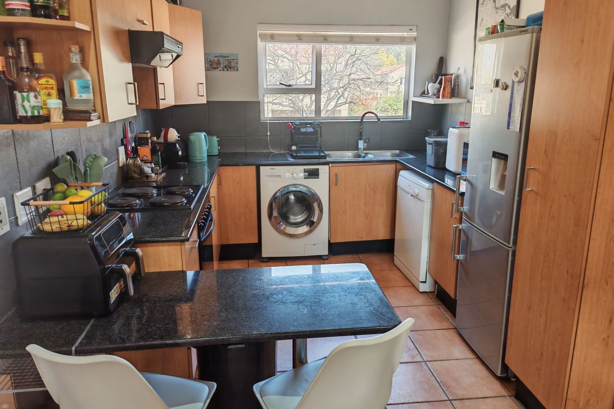 Functional kitchen featuring laminate cabinetry, granite countertops, tiled backsplash, and integrated space for laundry appliances and a breakfast nook.