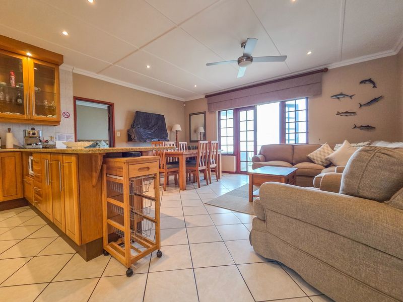 Open-plan living and dining area featuring tiled floors, a functional kitchen with granite countertops, and direct access to a balcony through french doors.