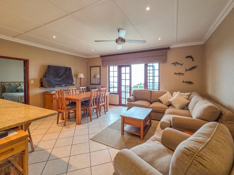 Spacious open-plan living and dining area featuring tiled flooring, recessed lighting, a ceiling fan, and direct access to an outdoor balcony through french doors.