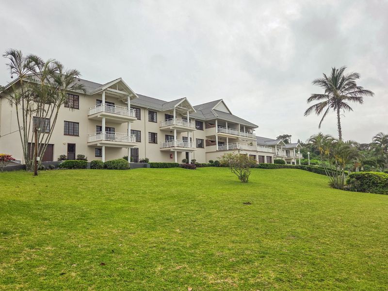A view of the rear elevation of a multi-story apartment complex featuring private balconies and well-maintained landscaped grounds.