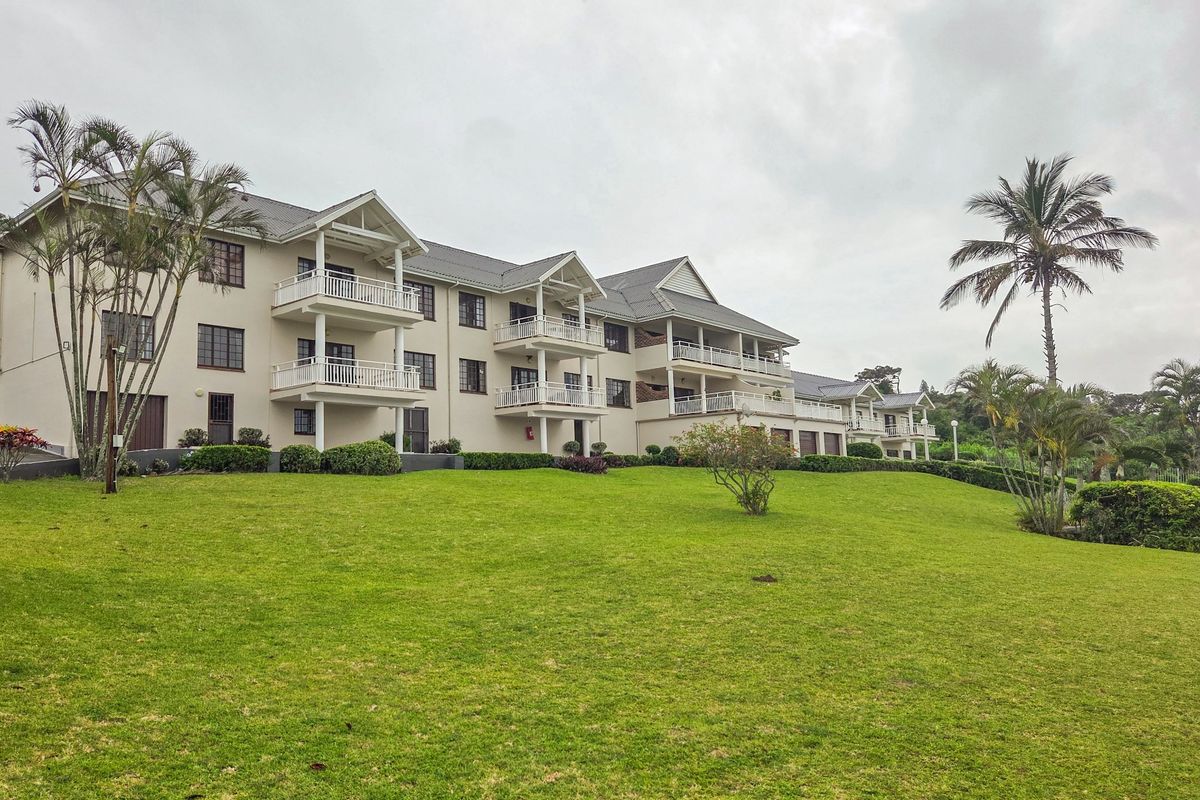 A view of the rear elevation of a multi-story apartment complex featuring private balconies and well-maintained landscaped grounds.