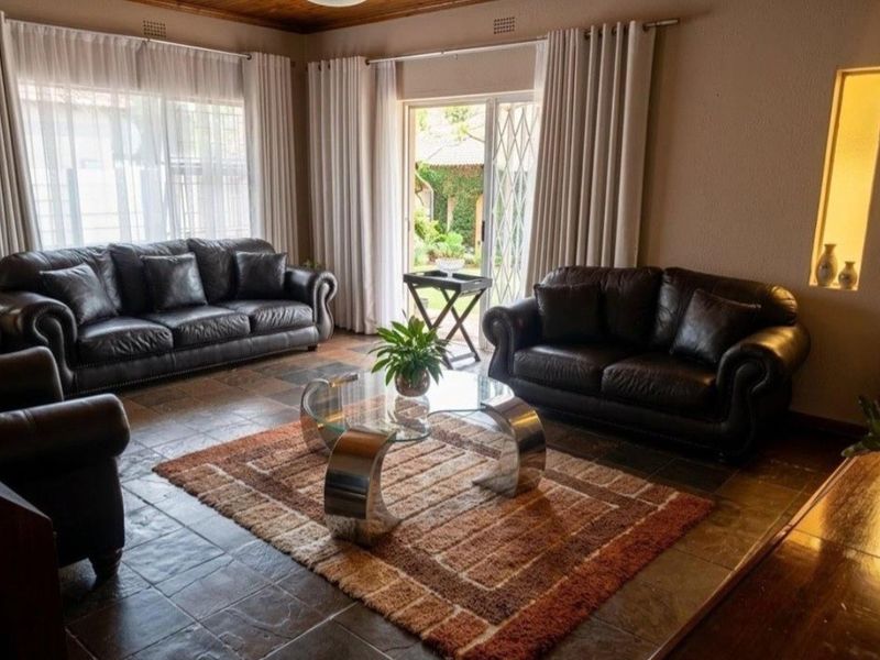 Spacious living room featuring slate tile flooring, a timber ceiling, and a sliding glass door providing direct access to the garden.