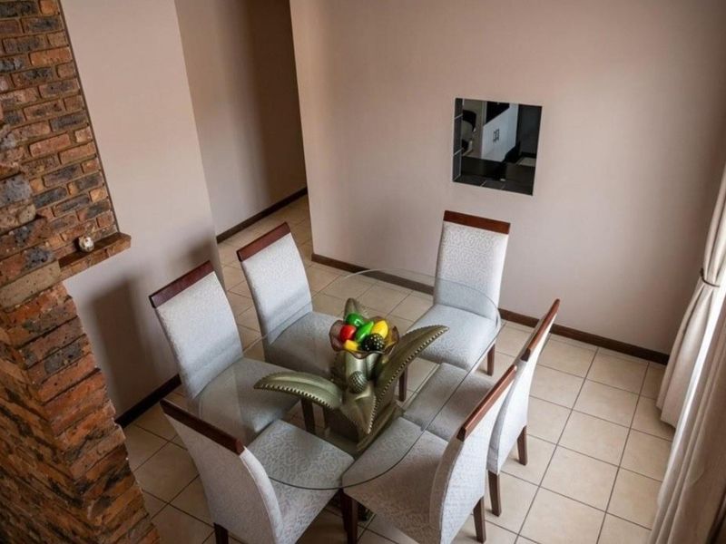 Dining area featuring ceramic floor tiles and an exposed brick feature wall with a recessed wall niche.