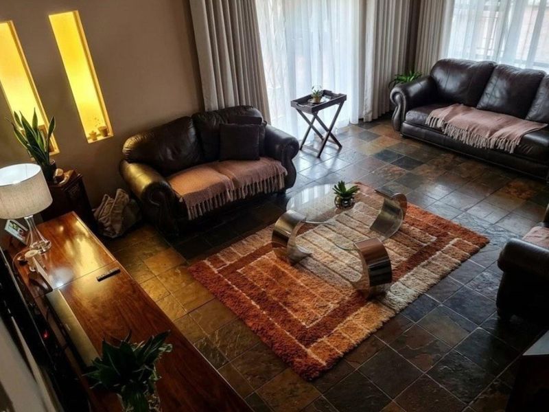A comfortable living room featuring slate tile flooring, recessed wall niches, and large sliding glass doors that provide ample natural light.
