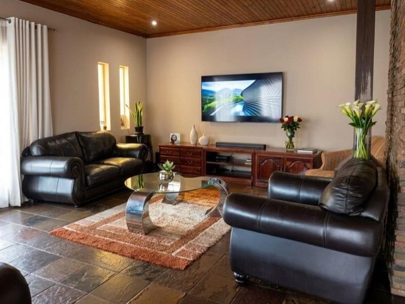 A comfortable living room featuring a warm timber ceiling, stone tile flooring, and an exposed brick feature wall, creating a cozy and inviting atmosphere.