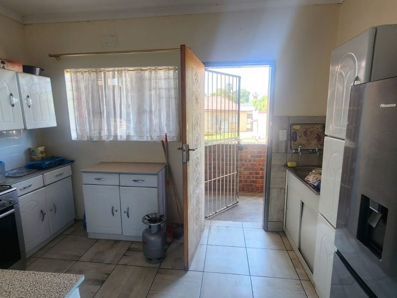 A functional kitchen featuring built-in cabinetry, a gas stove, and direct access to an exterior area through a security gate.
