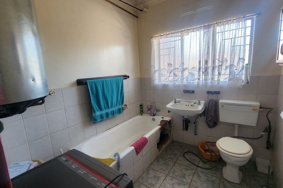 A dated bathroom featuring a bathtub with missing side panel, pedestal sink, and toilet, requiring significant renovation and repair of fixed finishes.