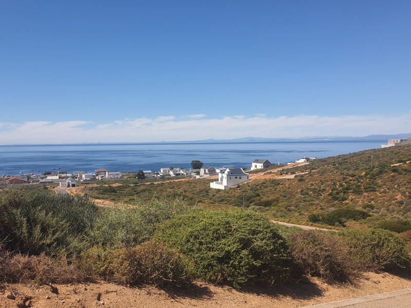 A scenic elevated view overlooking the coastline, surrounding residential properties, and the ocean, showcasing the natural landscape and coastal setting.